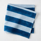 Folded Blue Tonal Hampton Stripe Cotton Napkin with bold and light blue stripes.