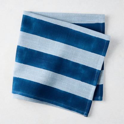 Folded Blue Tonal Hampton Stripe Cotton Napkin with bold and light blue stripes.