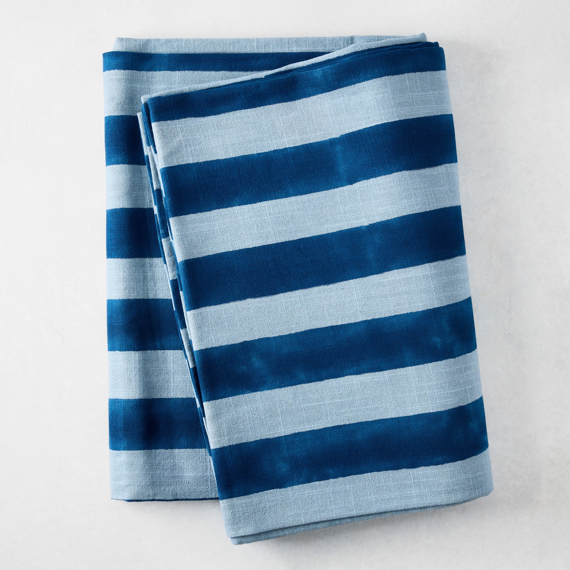 Blue Tonal Hampton Stripe Cotton Tablecloth, 70"W x 108"L, folded with bold and light blue stripes.