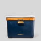 Navy blue 55-quart Hemingway cooler with acacia wood lid, white cushion, and stainless steel latch on gray background.
