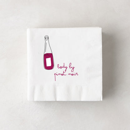 White 3-ply paper cocktail napkin with a red wine bottle illustration and "body by pinot noir" text.