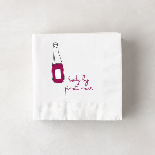 White 3-ply paper cocktail napkin with a red wine bottle illustration and "body by pinot noir" text.