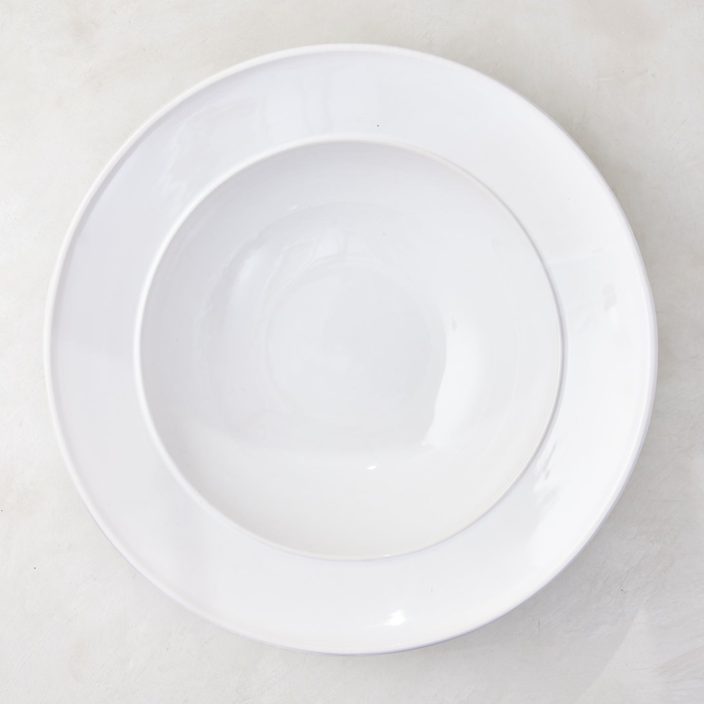 Bolinas 16" white ceramic round serve bowl with a raised edge trim.