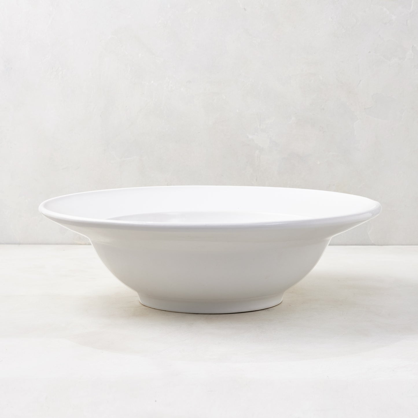 Bolinas 16" white ceramic serve bowl with a raised edge trim, handmade in Italy.