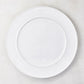 White round ceramic serving platter with a raised trimmed edge.