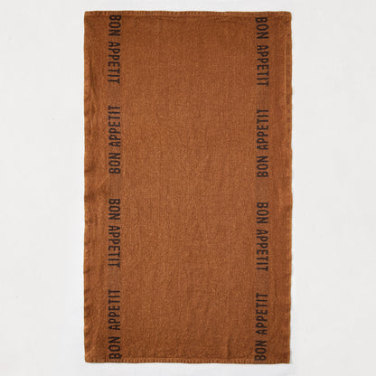 Brown linen hand towel with "BON APPETIT" printed vertically in black on both sides.