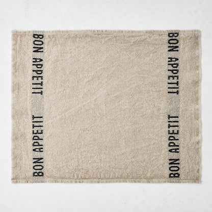 Camel khaki linen napkin with "BON APPETIT" in black lettering on two vertical stripes.
