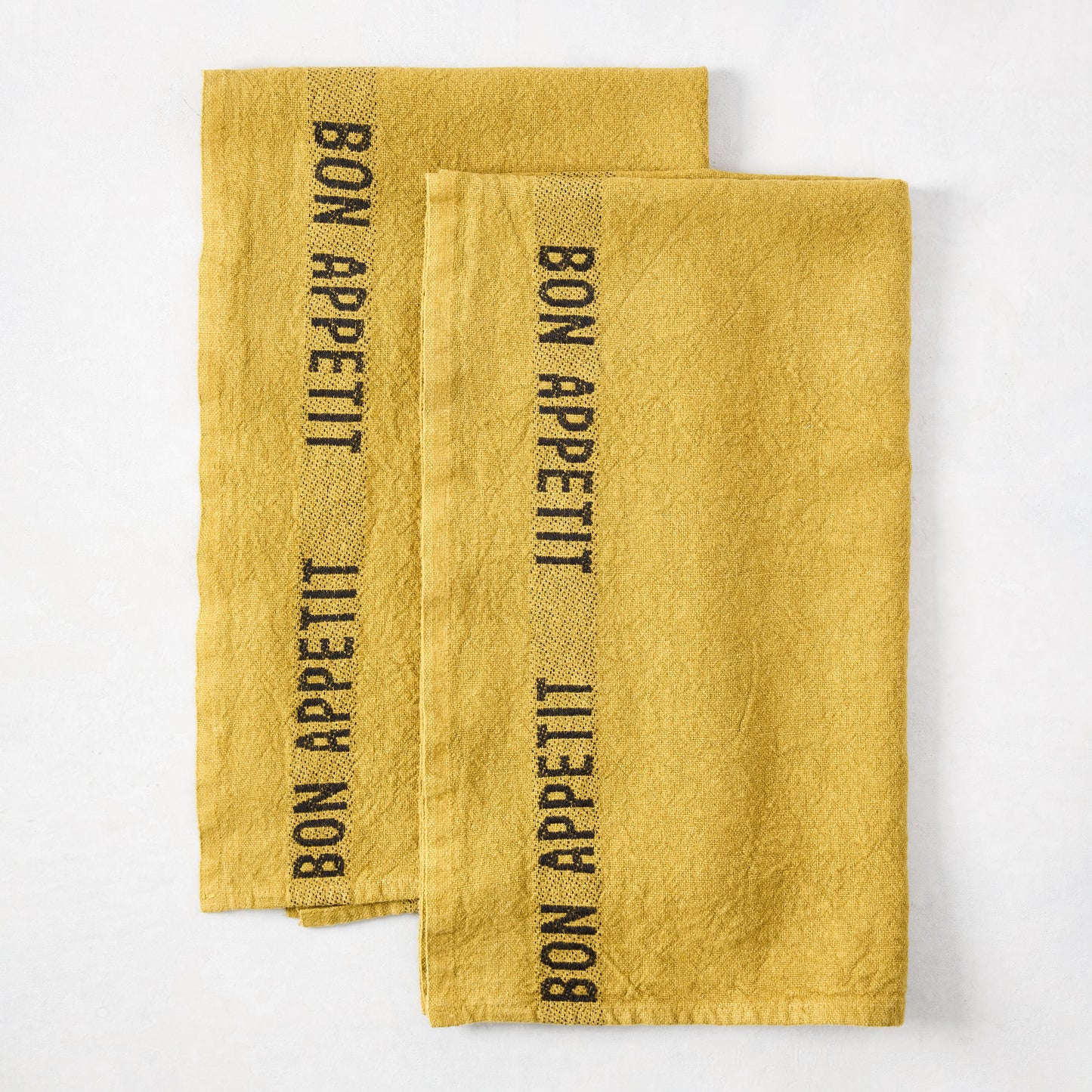 Set of 2 Goldenrod Yellow Linen Hand Towels with "BON APPETIT" in black lettering.