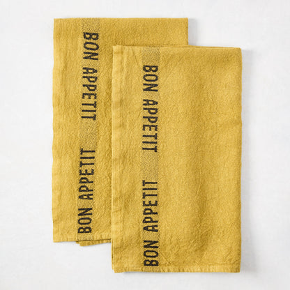 Set of 2 Goldenrod Yellow Linen Hand Towels with "BON APPETIT" in black lettering.
