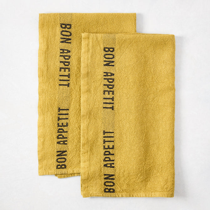 Set of 2 Goldenrod Yellow Linen Hand Towels with "BON APPETIT" in black lettering.