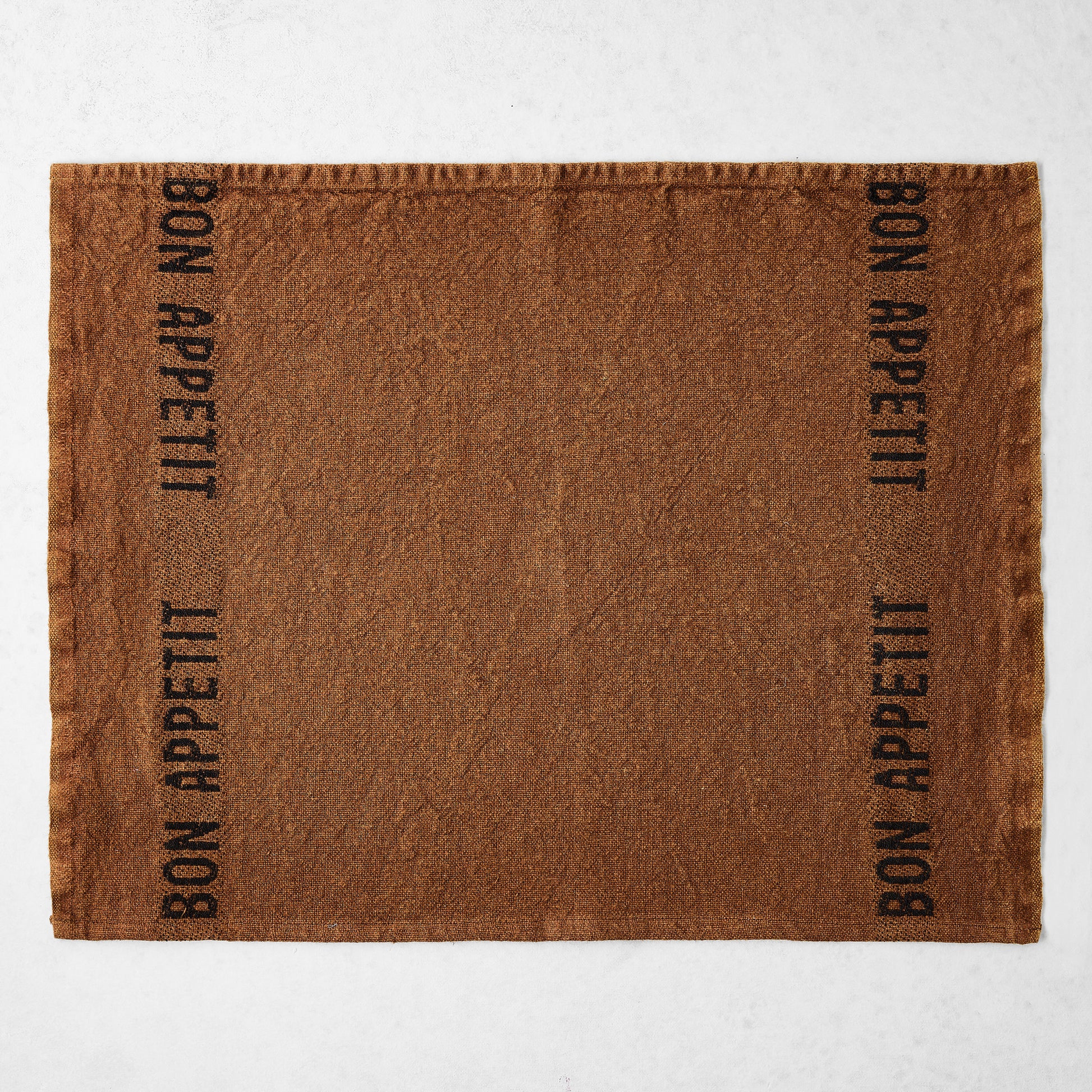 Havane brown linen napkin with "Bon Appetit" in black lettering on both sides.