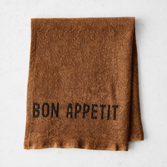 Folded Havane Brown linen napkin with "BON APPETIT" in black lettering.