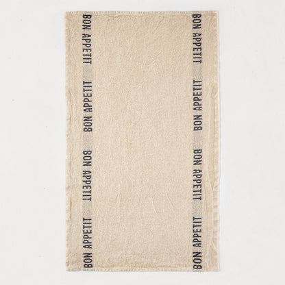 Khaki linen hand towel with "BON APPETIT" printed vertically in black on both sides.
