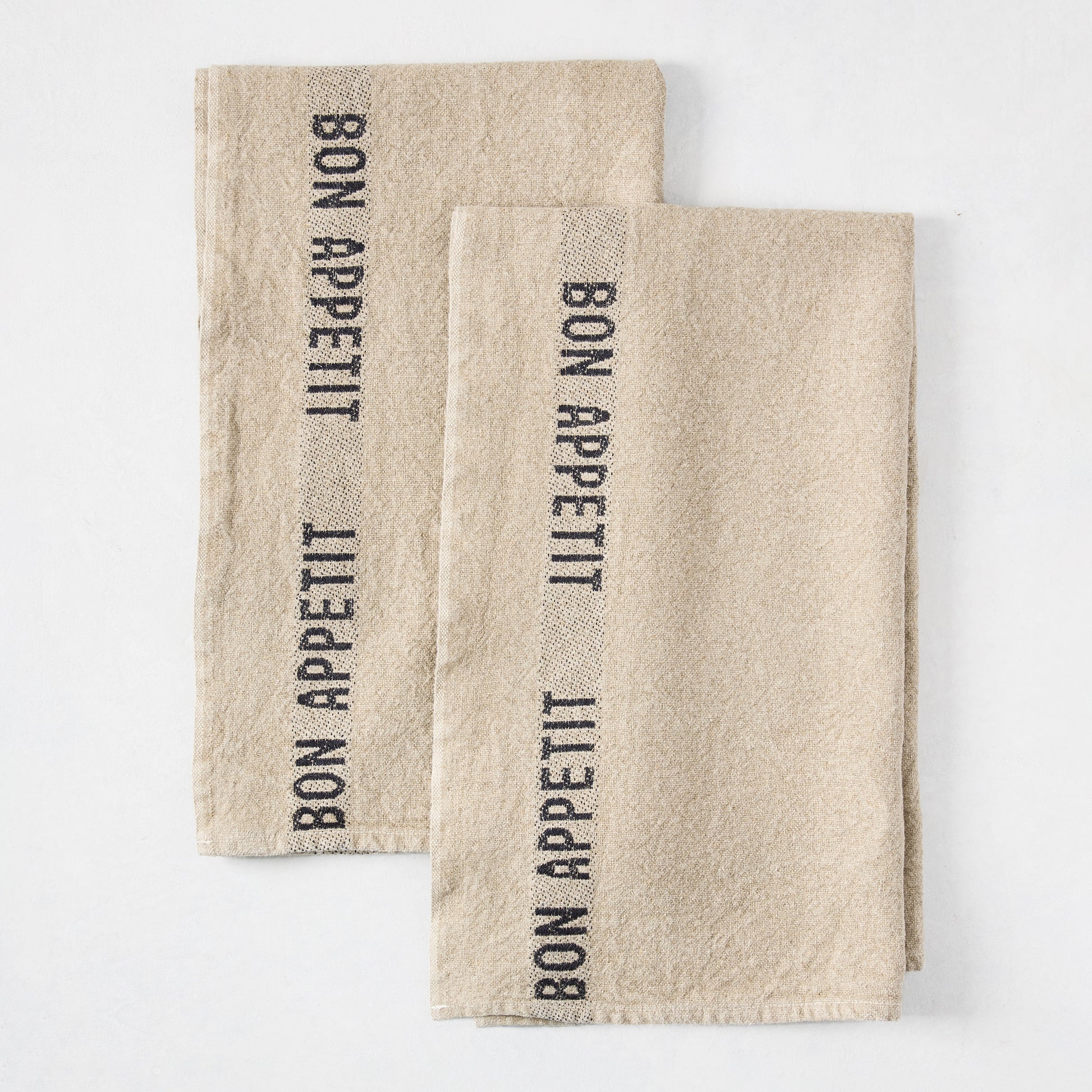 Set of 2 khaki linen hand towels with "BON APPETIT" in black lettering, folded on a white surface.