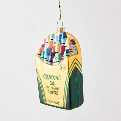 Hand-painted glass ornament shaped like a vintage box of 24 colorful crayons with glitter accents.