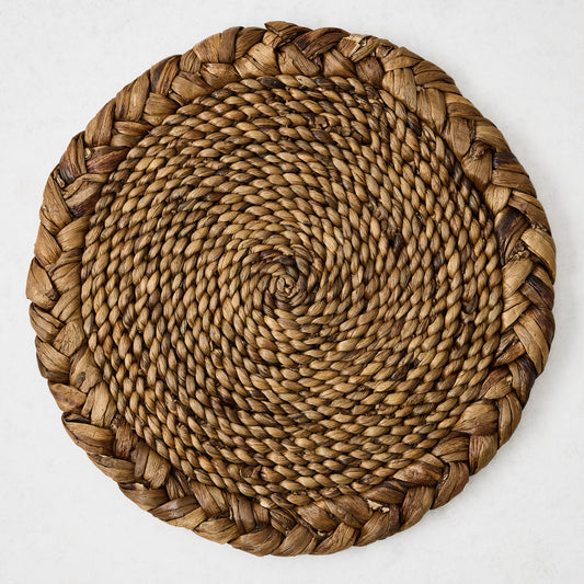 16-inch round braided water hyacinth placemat in honey-brown with a textured spiral center and thick woven border.