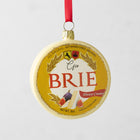 Round, hand-painted glass Brie cheese Christmas ornament with gold glitter trim and red ribbon.