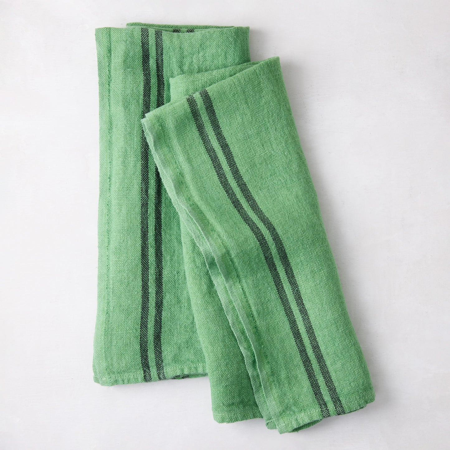 Set of 2 bright green French linen towels with dark gray stripes, folded.