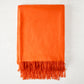 Bright orange cashmere throw blanket with fringe.
