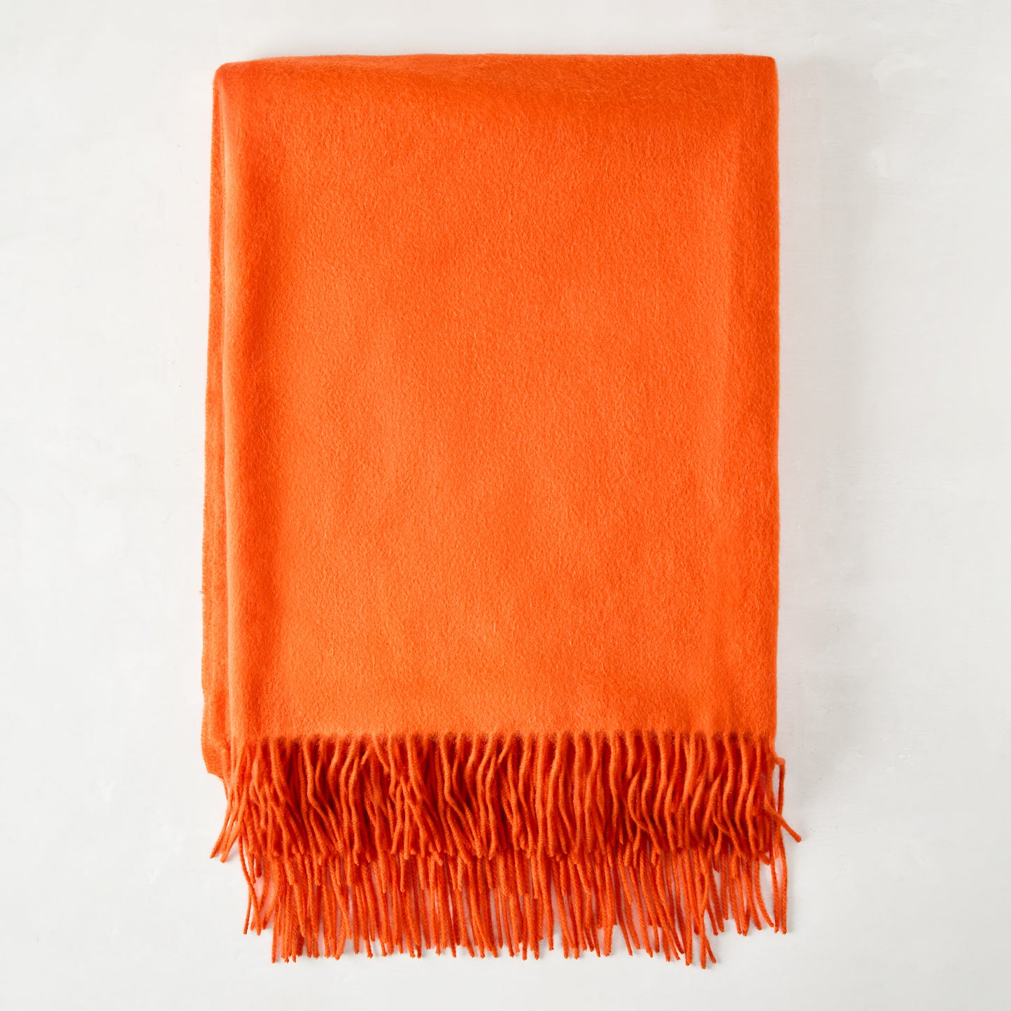 Bright orange cashmere throw blanket with fringe.