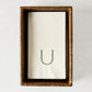 Brown woven rattan rectangular hand towel holder with white folded hand towels.