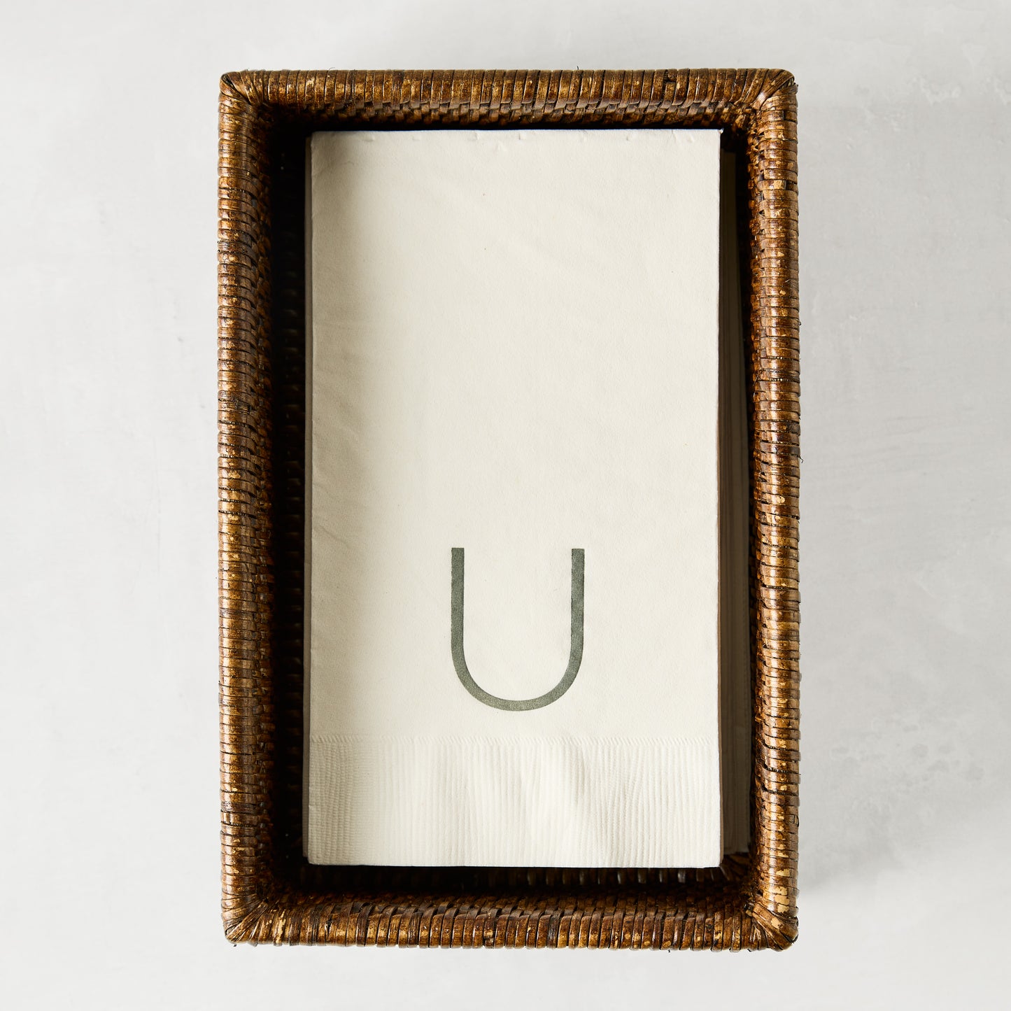 Brown woven rattan rectangular hand towel holder with white folded hand towels.