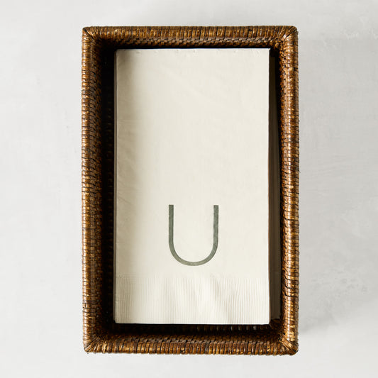 Brown woven rattan rectangular hand towel holder with white folded hand towels.