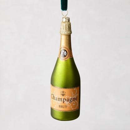 6-inch mouth-blown glass champagne bottle ornament in matte green with gold glitter accents and a velvet hanging loop.