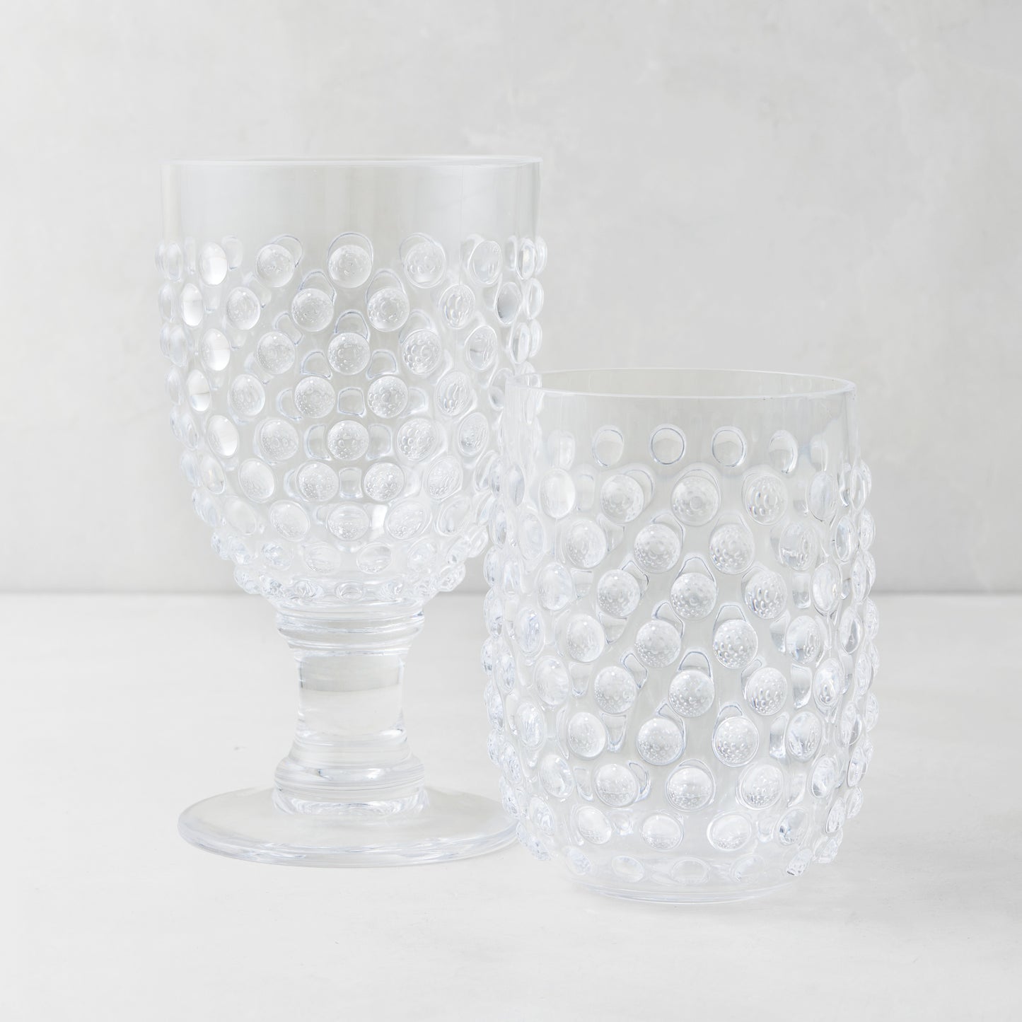 Clear acrylic bubble wine glass and tumbler with textured hobnail design.