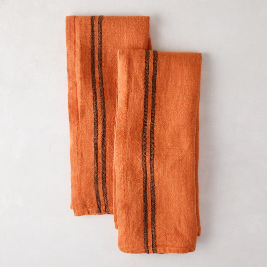 Set of 2 burnt orange French linen towels with dark brown stripes, folded on a white surface.