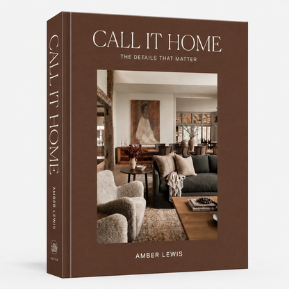 The front and spine of the book 'Call It Home: The Details That Matter' by Amber Lewis, featuring a warm brown cover with a central photograph of a cozy living room.
