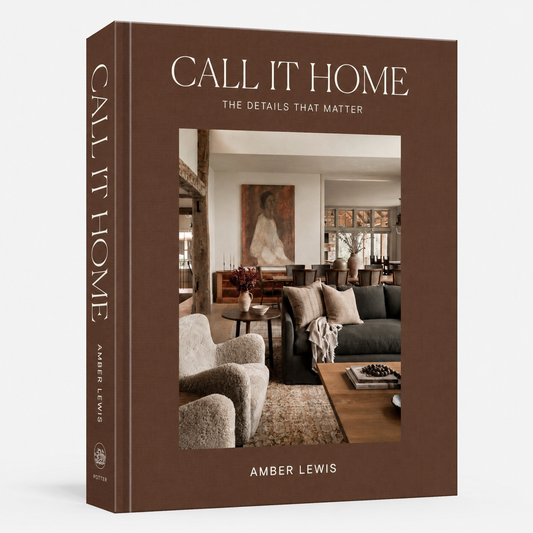 The front and spine of the book 'Call It Home: The Details That Matter' by Amber Lewis, featuring a warm brown cover with a central photograph of a cozy living room.