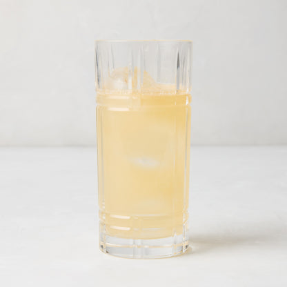 Camden Eco-Crystal High Ball Glass, clear, sleek, slender, filled with a light yellow drink and ice.