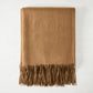 Folded camel brown cashmere throw blanket with classic fringe.