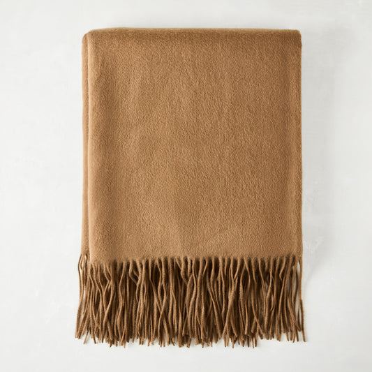 Folded camel brown cashmere throw blanket with classic fringe.