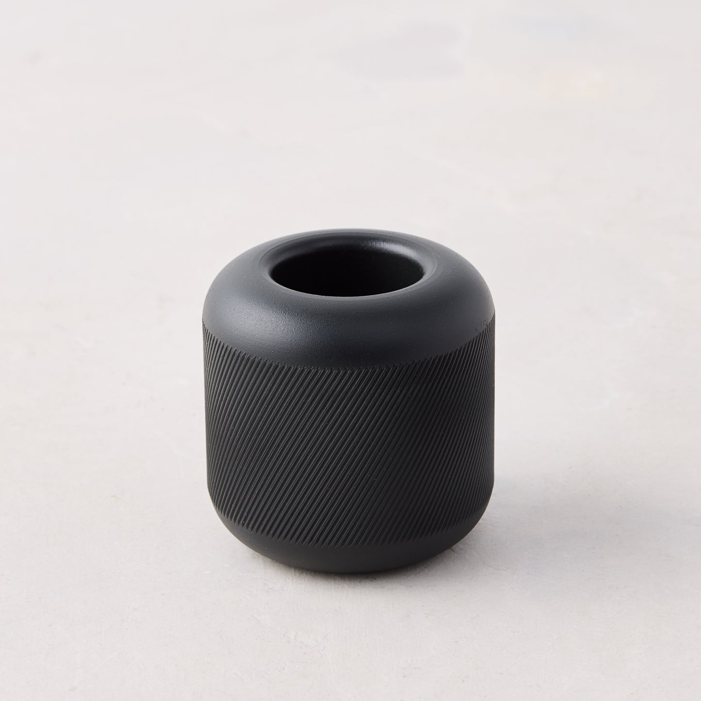 Black cast iron match striker with deep knurling pattern on the exterior, 2"x2"x2".