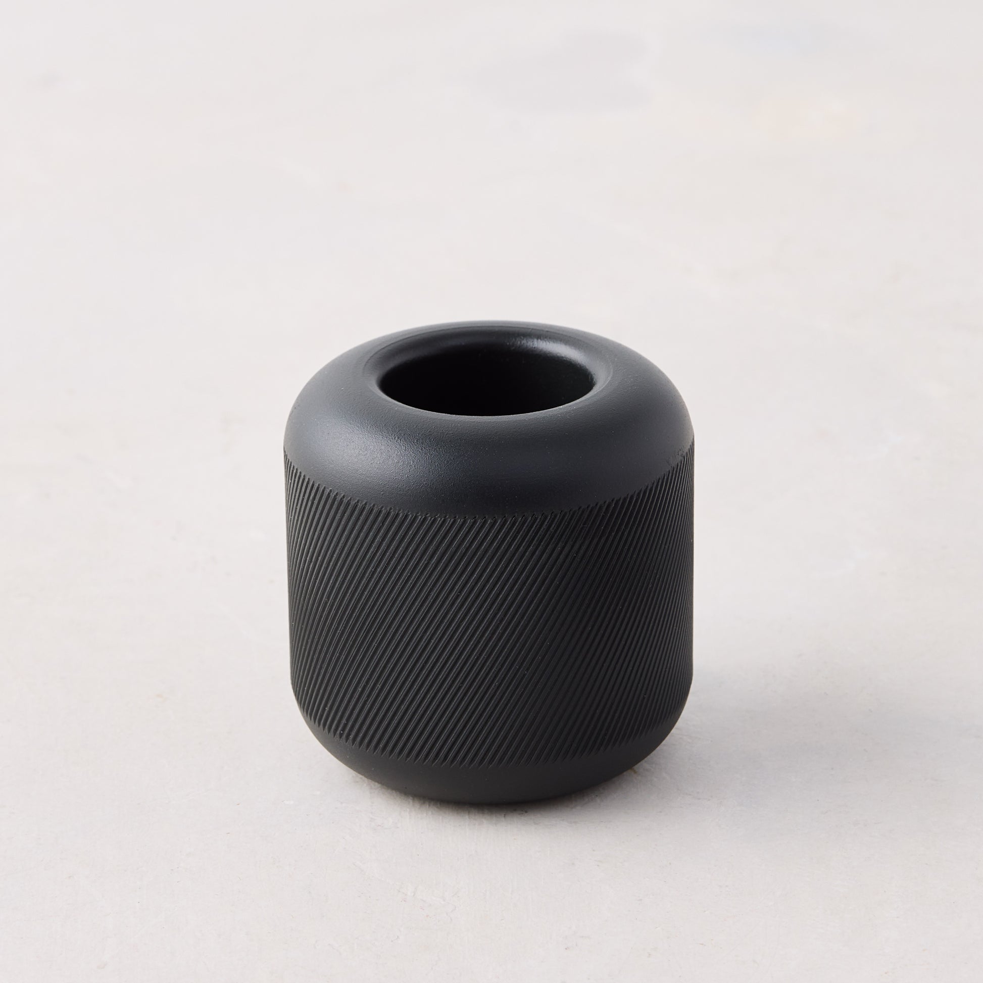 Black cast iron match striker with deep knurling pattern on the exterior, 2"x2"x2".