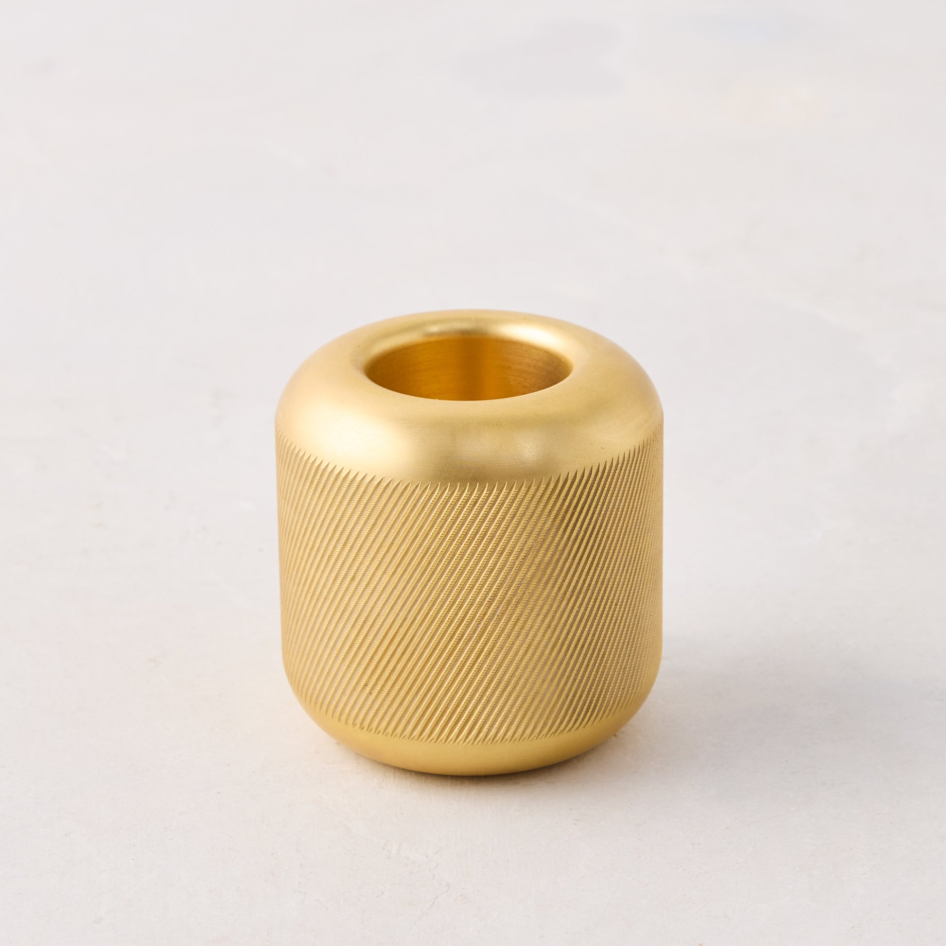 Brass match striker, 2x2x2, with a deep knurling pattern on the exterior surface.