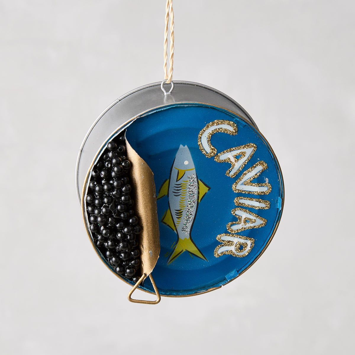 3-inch round caviar tin Christmas ornament made of glass and resin with hand-painted blue, gold, and black details.