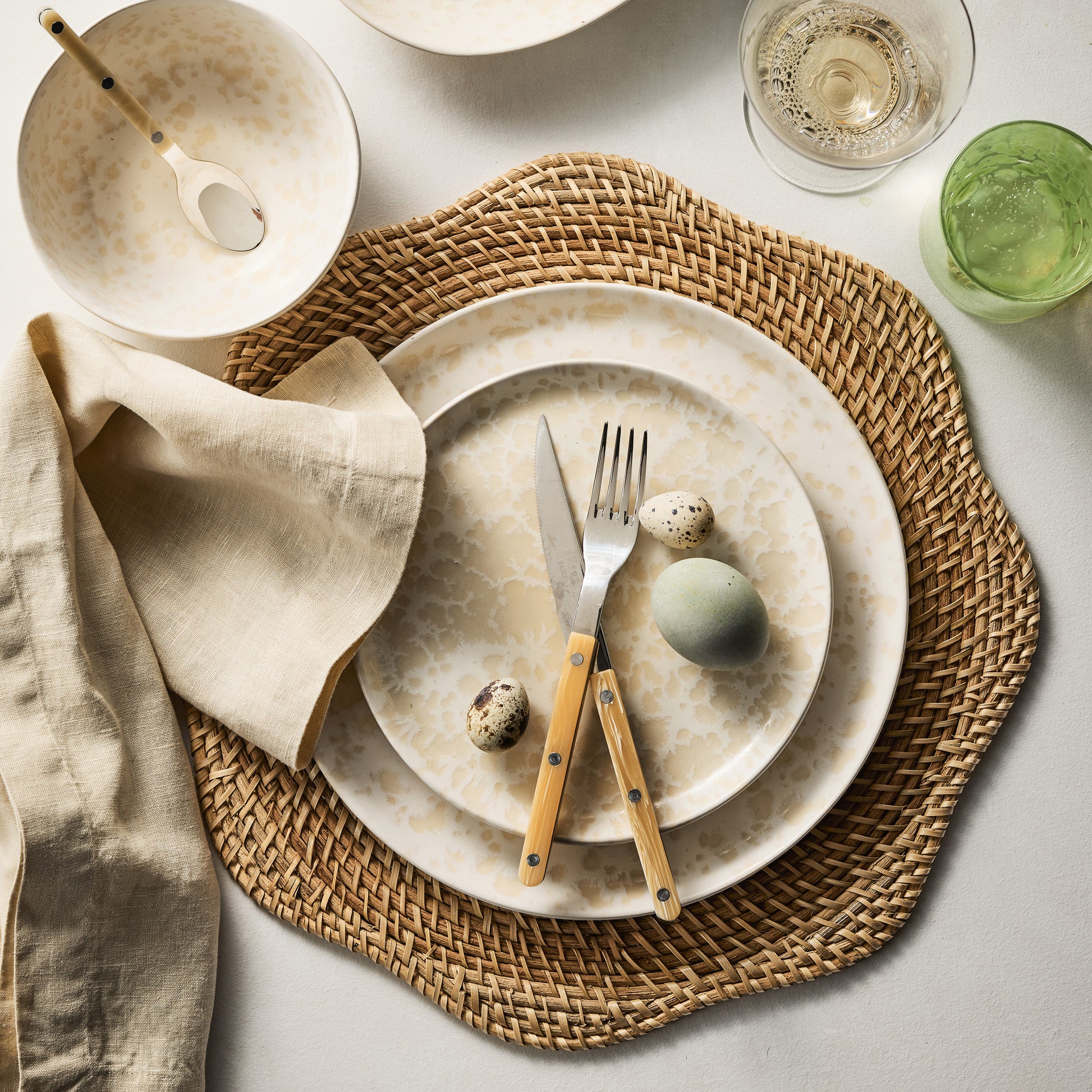 Honey-brown Cebu Scalloped Hapao Placemat, 16" rattan weave, under speckled plates and cutlery.