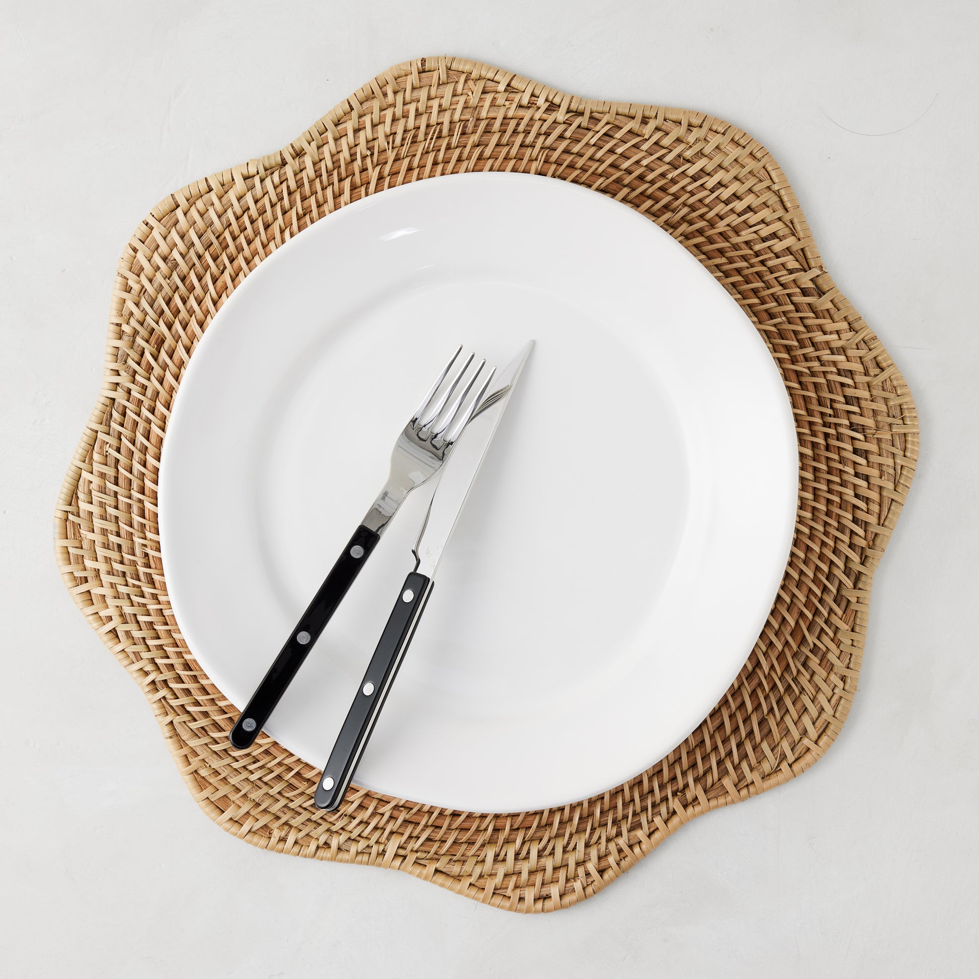 16" Cebu Scalloped Hapao Placemat, handcrafted honey-brown rattan with a traditional weave.