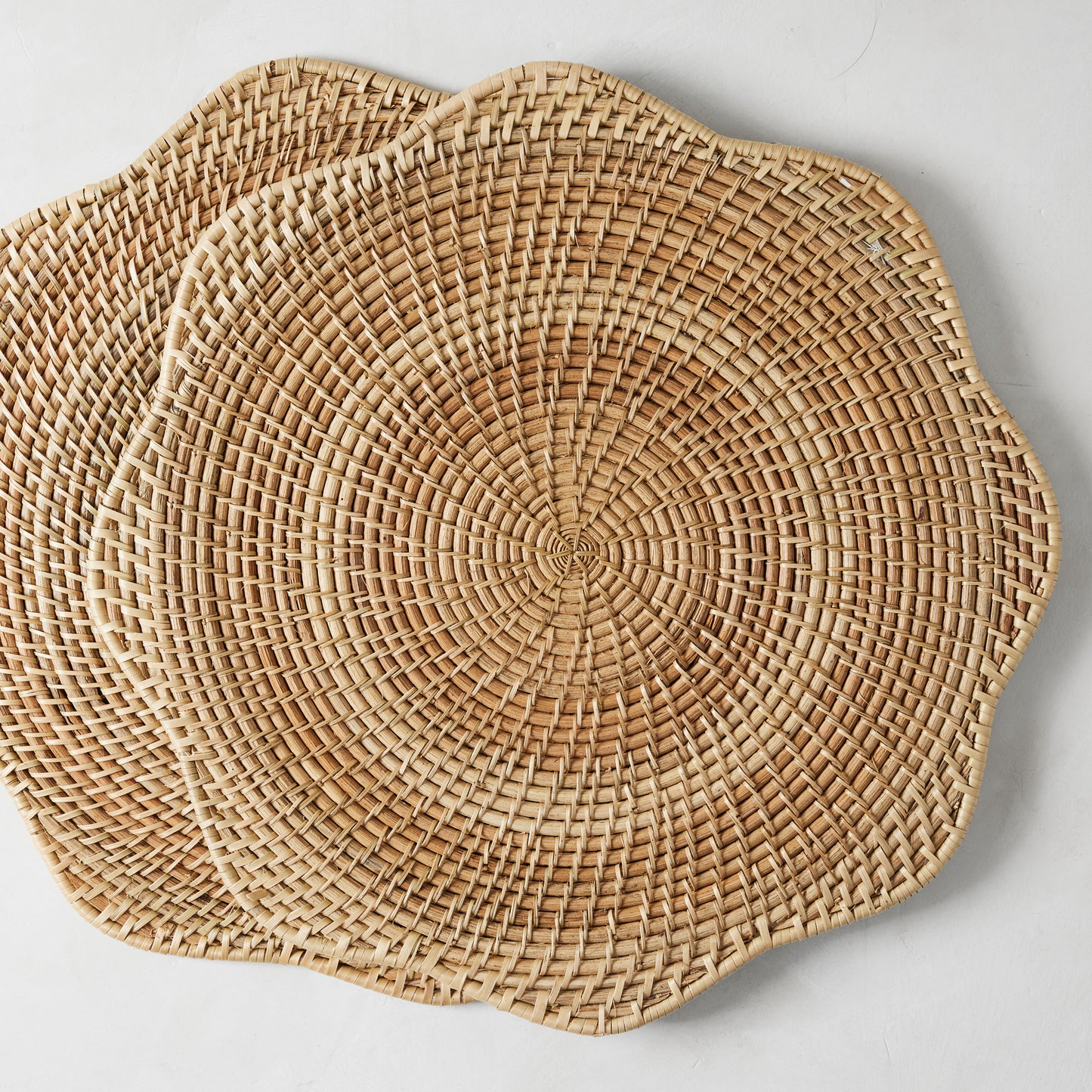 Two round Cebu Scalloped Hapao Placemats, 16.5" diameter, made of honey-brown rattan with a woven pattern.