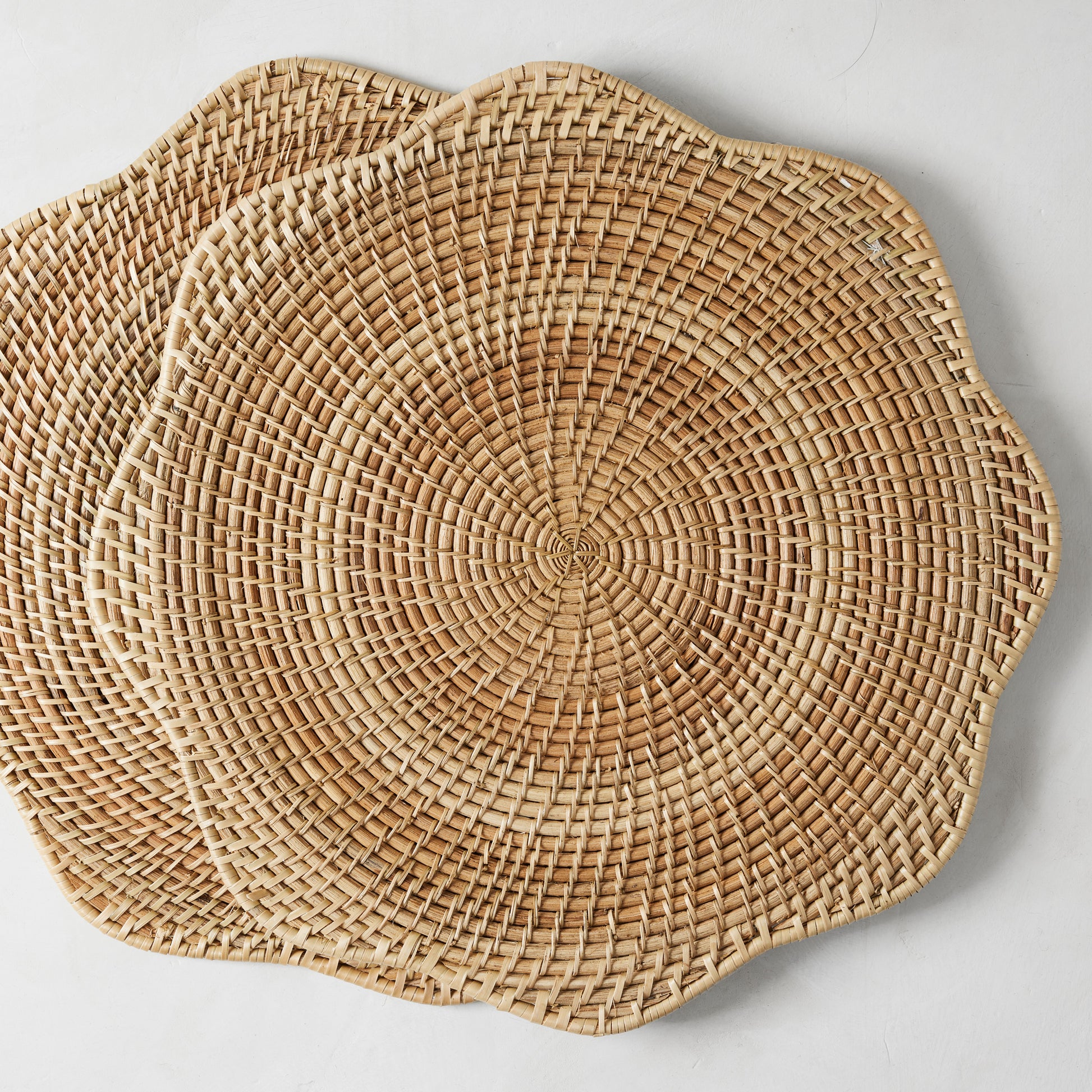 Two round Cebu Scalloped Hapao Placemats, 16.5" diameter, made of honey-brown rattan with a woven pattern.