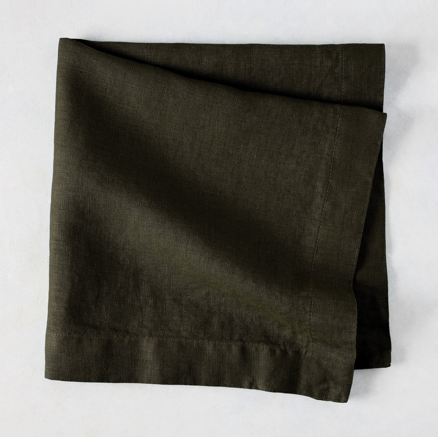 Cedar HG Signature Hand-Dyed Linen Napkin, dark mossy green, folded square, 22-inch.