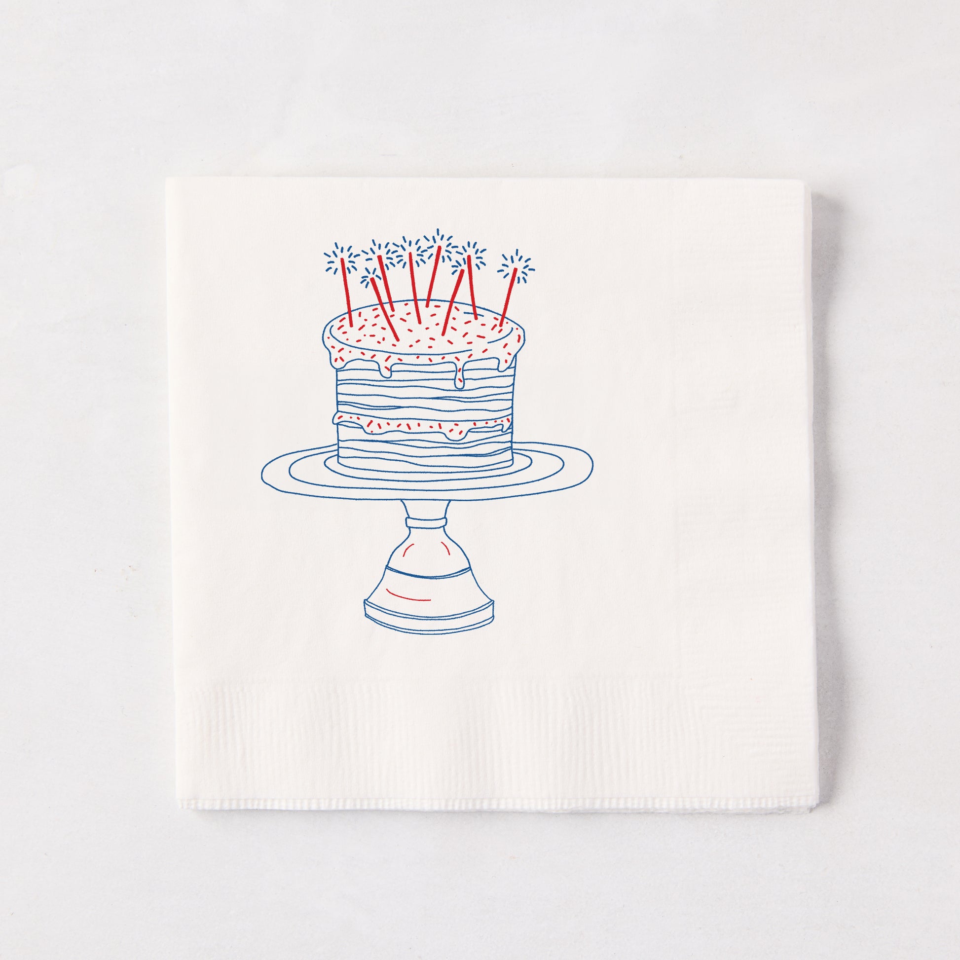 White 3-ply paper cocktail napkin with a blue and red "Celebration Cake" design, 5.5" square.