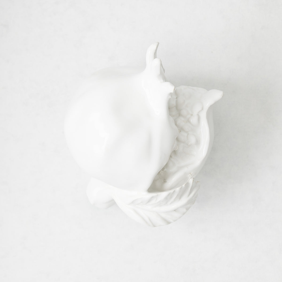 Handmade white glazed ceramic pomegranate decorative sculpture with artisanal details, 11 inches long.