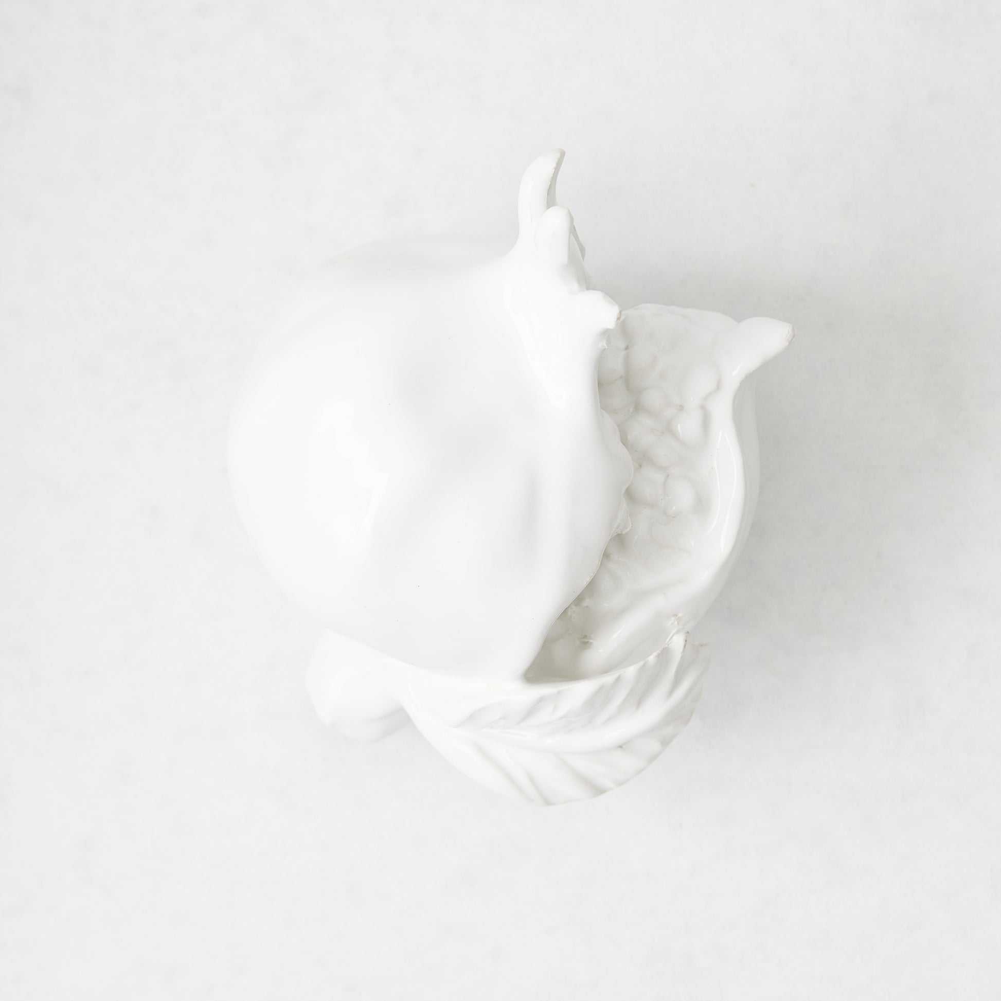 Handmade white glazed ceramic pomegranate decorative sculpture with artisanal details, 11 inches long.