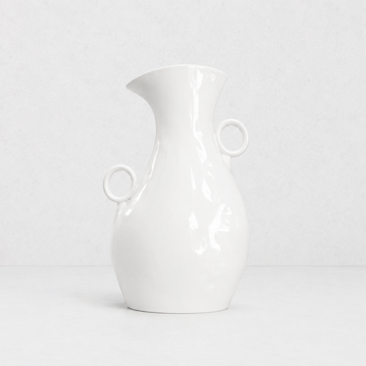 Creamy white ceramic pitcher by Montes Doggett, 14"H, with two round handles and a spout.
