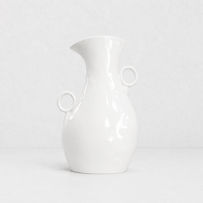 Creamy white ceramic pitcher by Montes Doggett, 14"H, with two round handles and a spout.