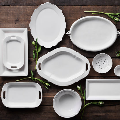 White ceramic serving platter with elegant handles on a rustic wood surface.